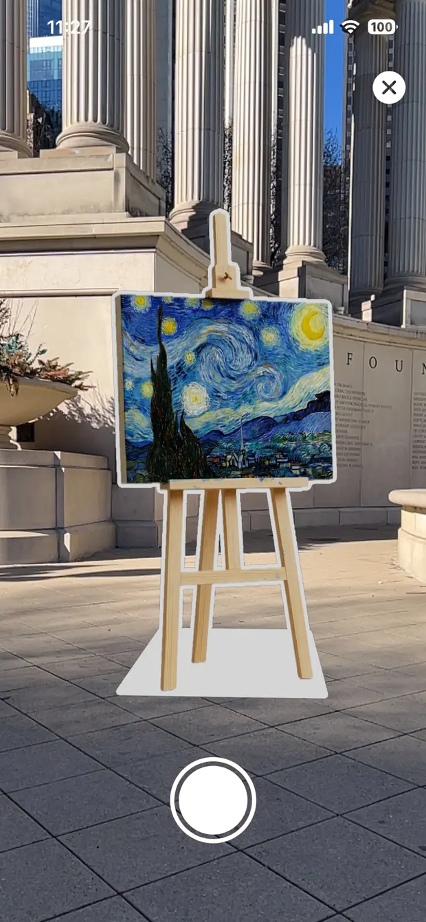 Augmented reality view: a cutout of a painting on a wooden easel, placed on a plaza outside a columned building.