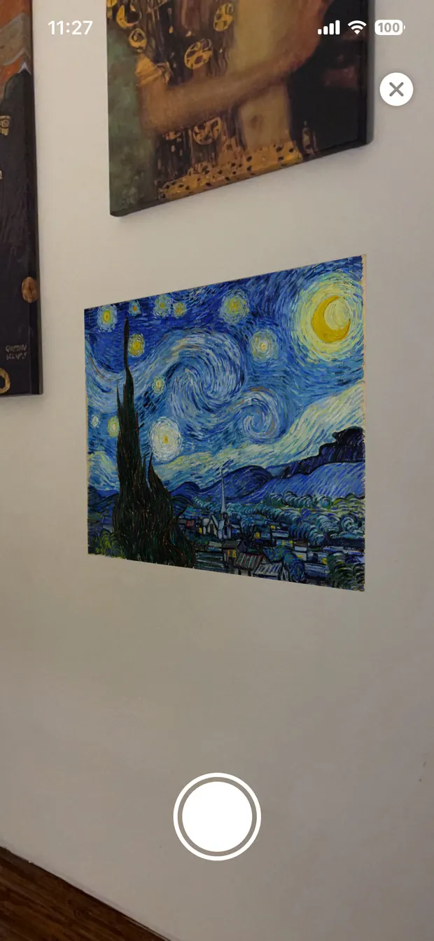 Augmented reality view: The Starry Night shown as a printed poster hanging flat on a pale wall, next to two real framed canvases.